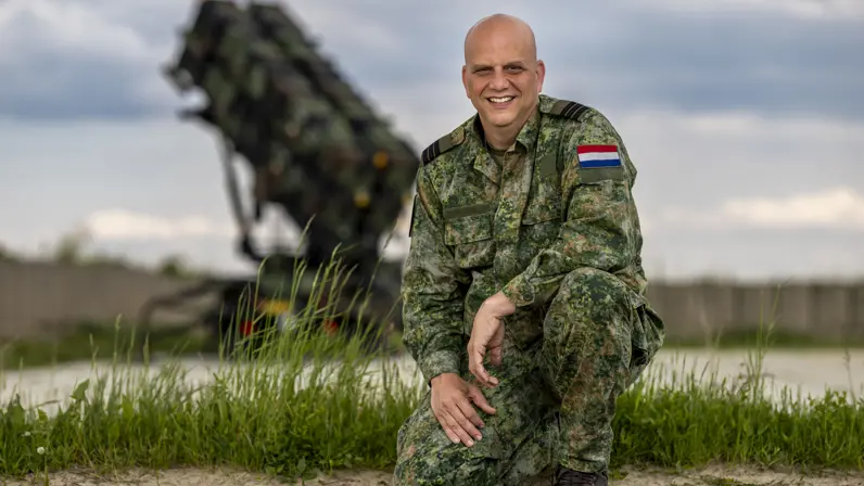 Commandant Van Empel zit gehurkt op één knie.