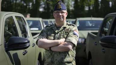 Op de linkerfoto kolonel Simon Wouda. Op de rechterfoto rijdt een voertuig een trein wagon op terwijl een militair hem gidst.