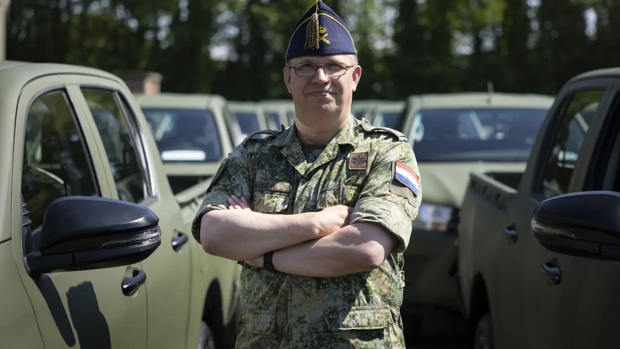 Op de linkerfoto kolonel Simon Wouda. Op de rechterfoto rijdt een voertuig een trein wagon op terwijl een militair hem gidst.