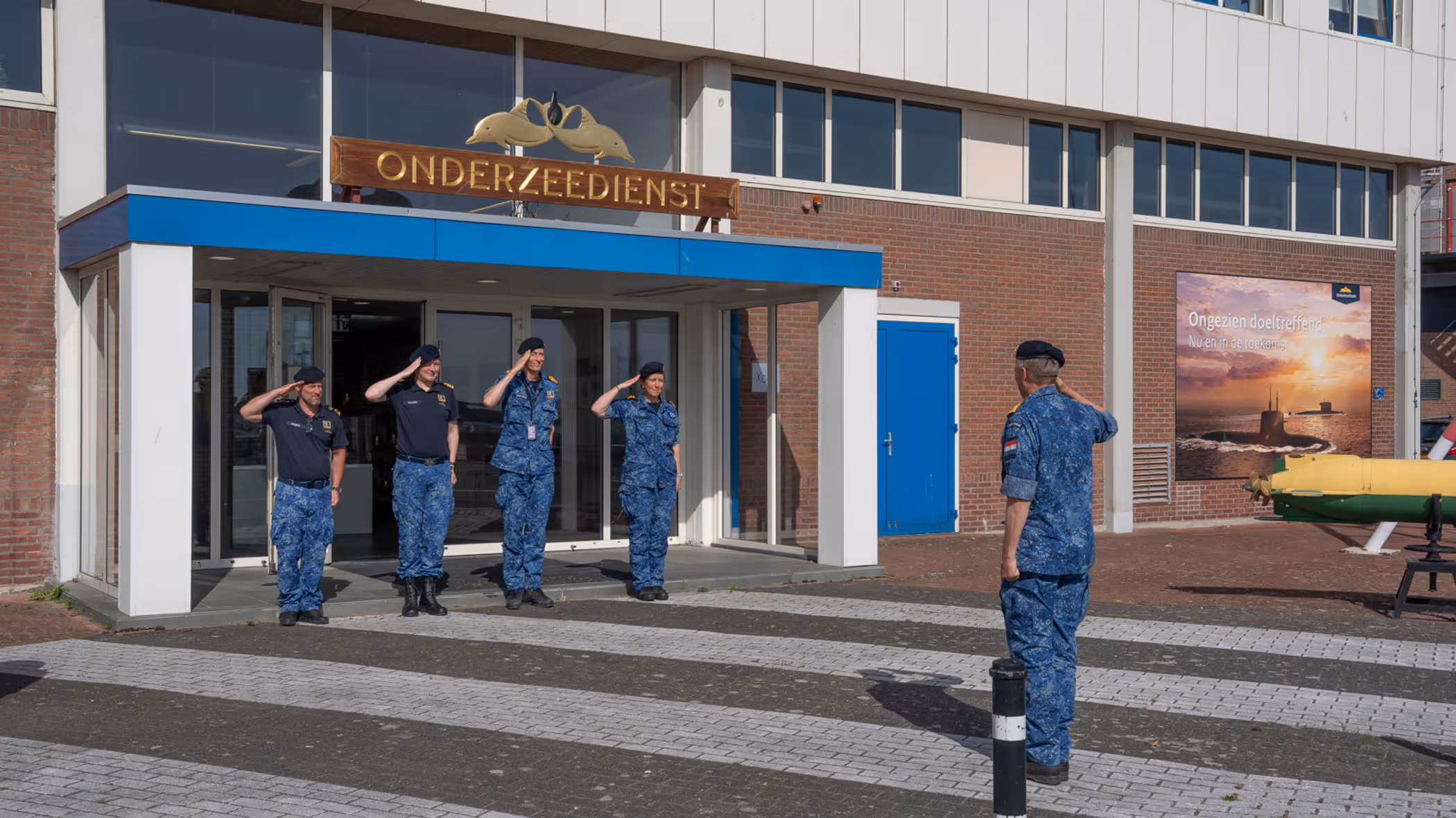 4 marinemensen staan in houding voor een hoge militair. 
