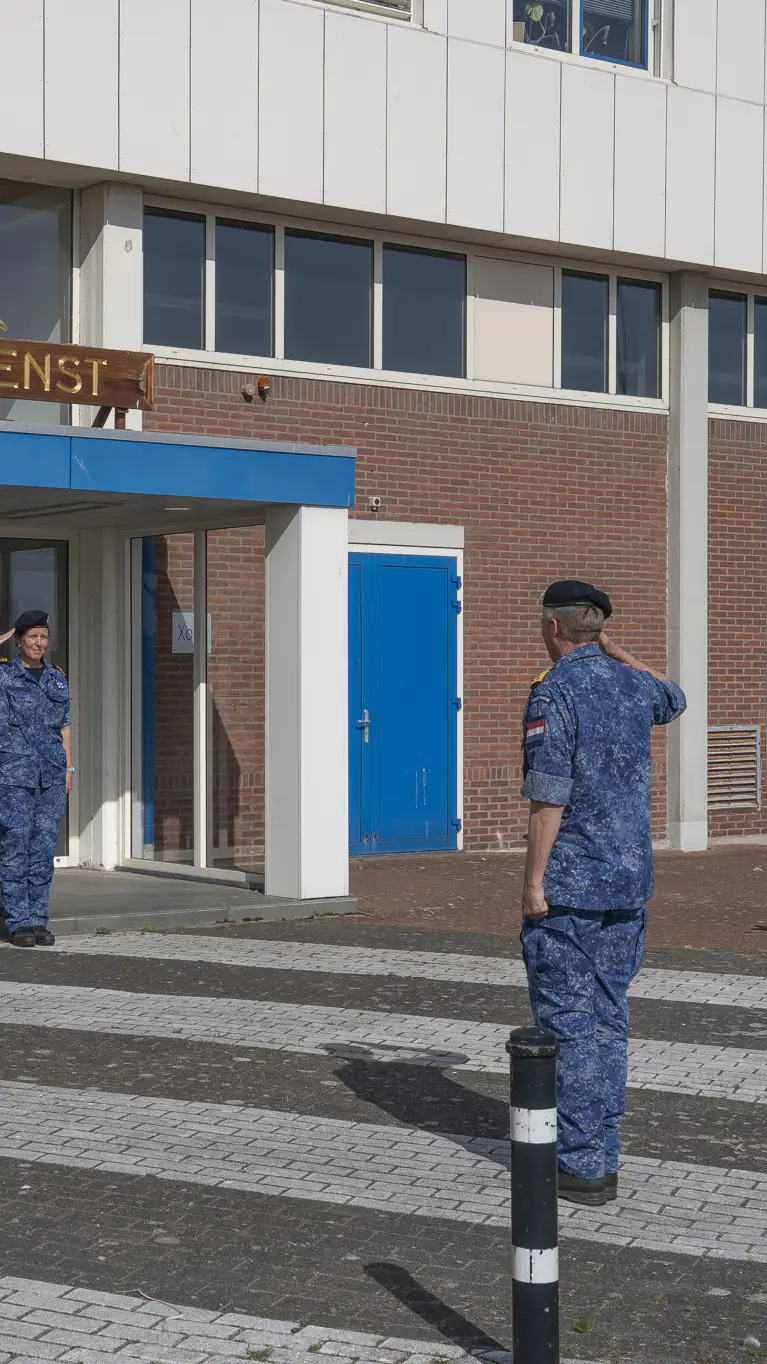  4 marinemensen staan in houding voor een hoge militair. 