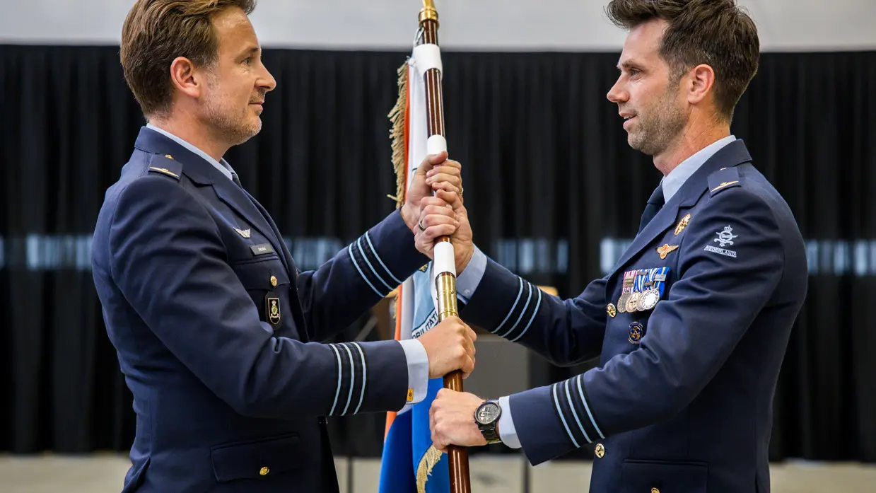 Jacobs overhandigt aan Hoogsteder op ceremoniële wijze een vlag.