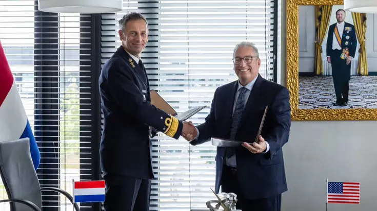 Militair en afgevaardigde bedrijf geven elkaar de hand na ondertekening overeenkomst.