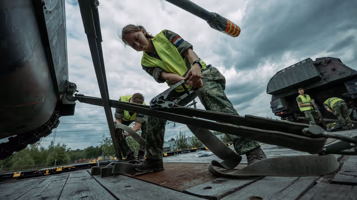 Militairen zetten zekeren militair voertuig voor vervoer per spoor.