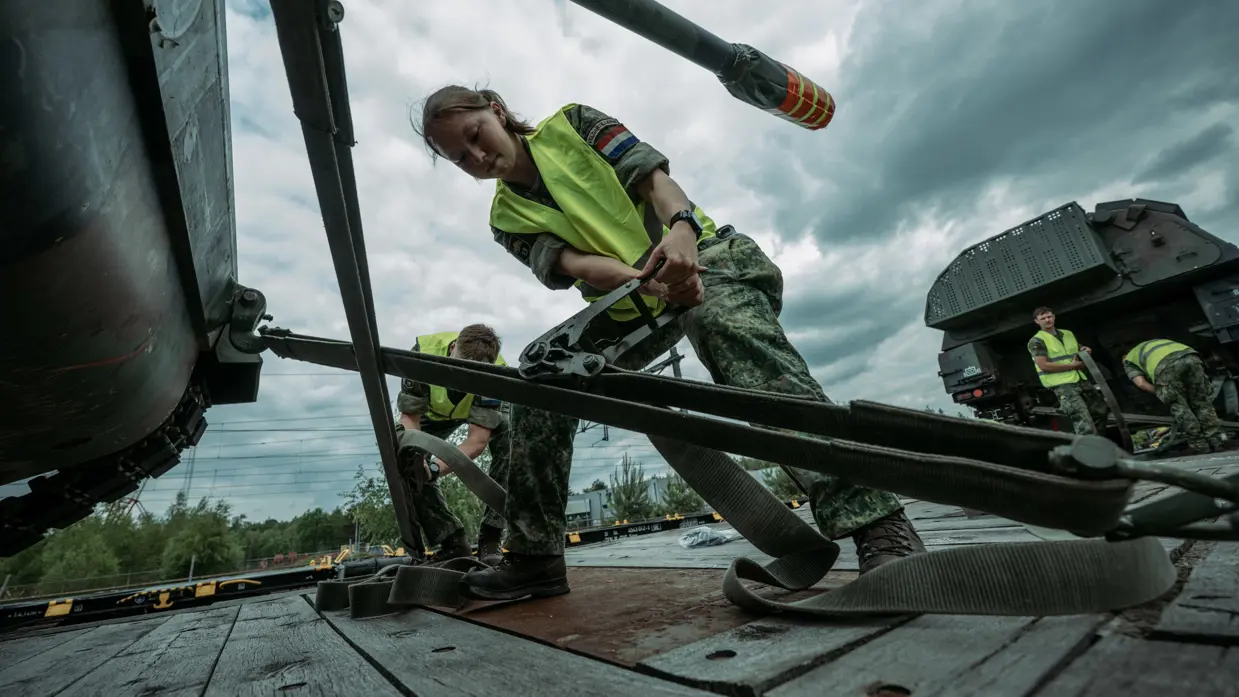 Militairen zetten zekeren militair voertuig voor vervoer per spoor.