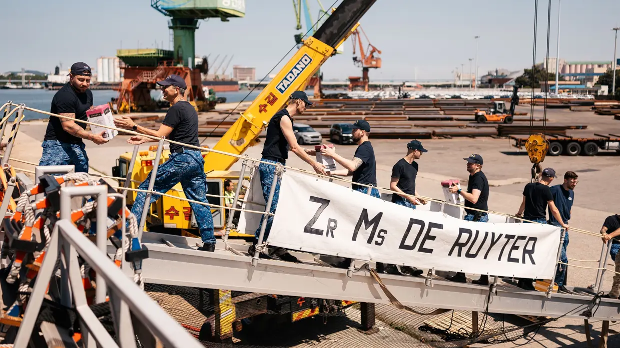 Een rij van militairen geeft materiaal aan elkaar door vanaf een haven naar het schip.