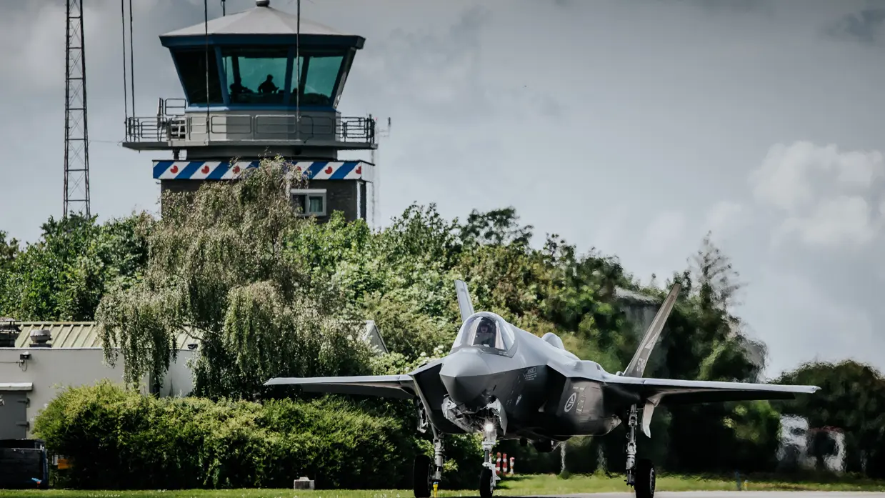 Een f35 op de startbaan met op de achtergrond de verkeerstoren.