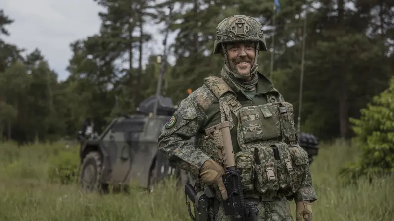 Luitenant-kolonel Marcel Kerstens staat tijdens oefening Fighter Lion voor een militair voertuig in een bosrijke omgeving.