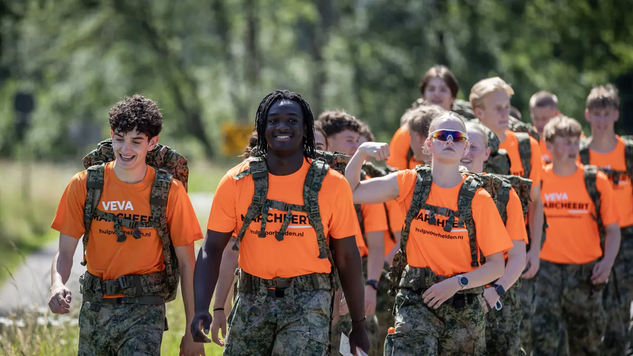 Een groep VeVa-studenten marcheert met oranje shirts aan.