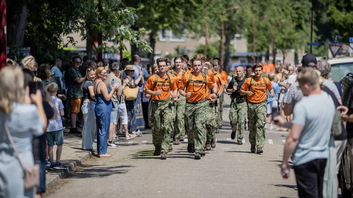 Een stoet van VeVa-studenten marcheert over straat temidden van een publiek.