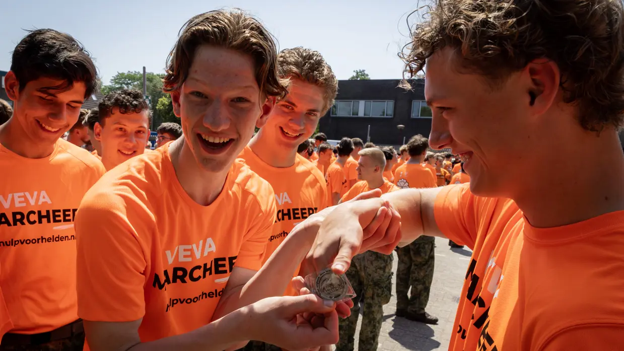 Enthousiaste VeVa-student toont zijn medaille, omringd door andere studenten.