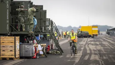 Een militair fiets over taxibaan waar een tijdelijke vliegbasis is opgebouwd.
