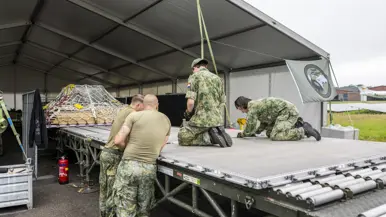 Militairen plaatsen materieel op pallets.