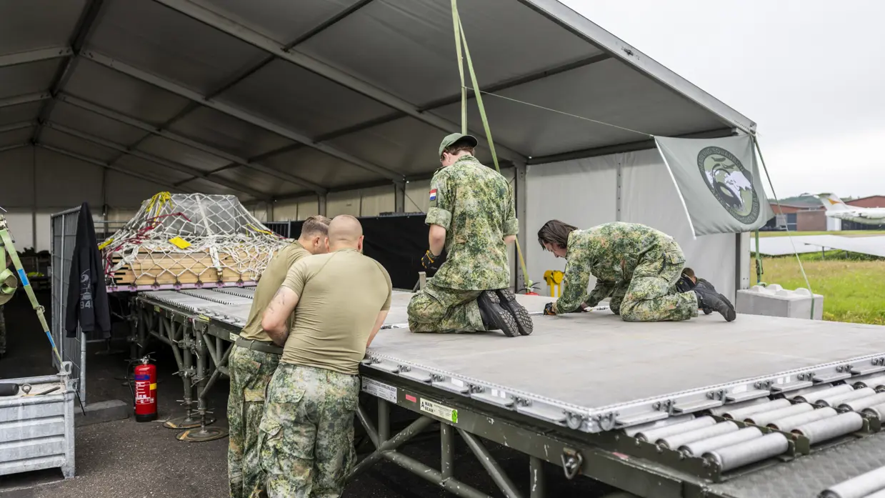 Militairen plaatsen materieel op pallets.