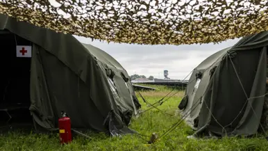  Twee groene legertenten met camouflagenetten.