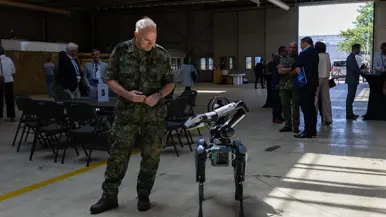 Commandant der Strijdkrachten Eichelsheim kijkt naar een robot. 