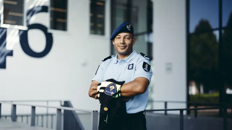 Wachtmeester Lesley in uniform, met een politieshirt over z’n armen.