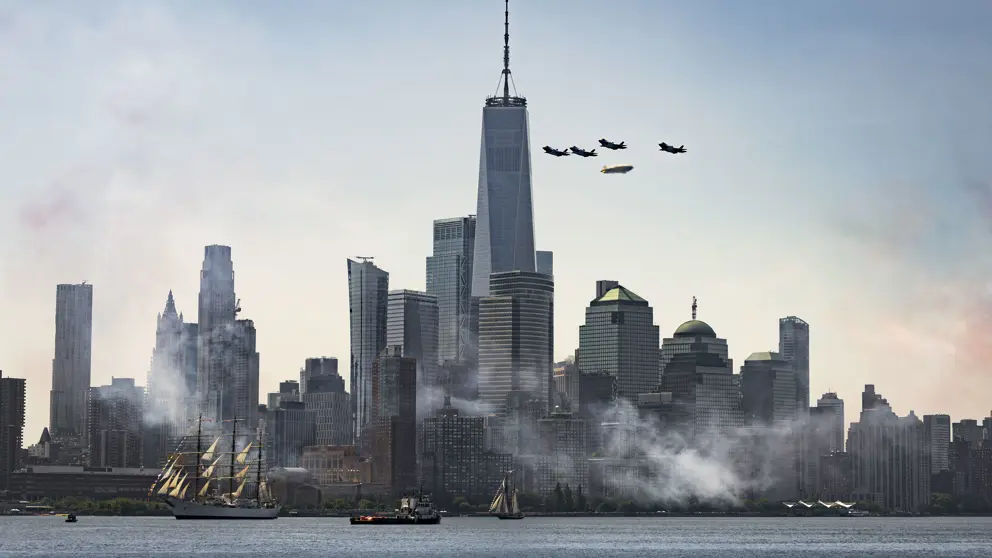 De Amerikaanse stad New York. Ervoor varen schepen en erboven vliegen militaire toestellen.