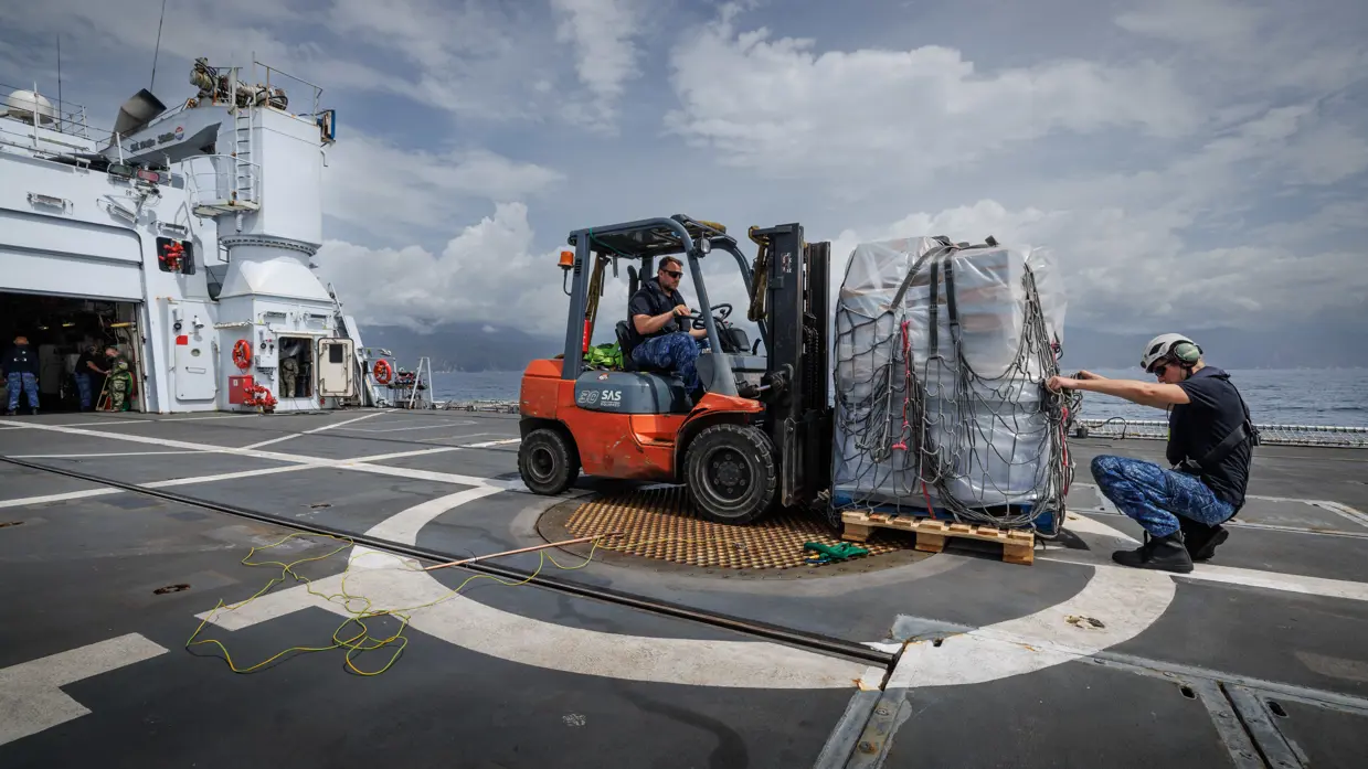 Een pallet met drinkwater wordt vervoerd met een vorkheftruck.