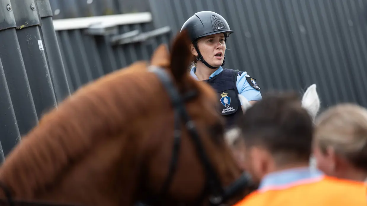 Tumult met meerdere mensen op de grond. Twee ruiters rijden er met hun paard naartoe.