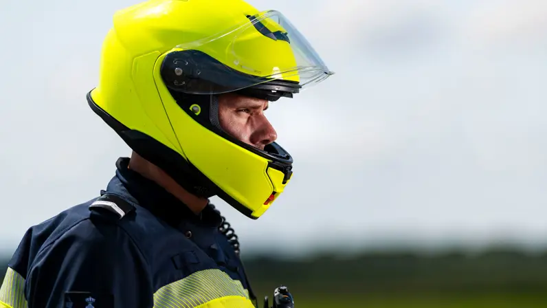 Close-up van wachtmeester Jesse, motorrijder van de Marechaussee, met zijn helm op.