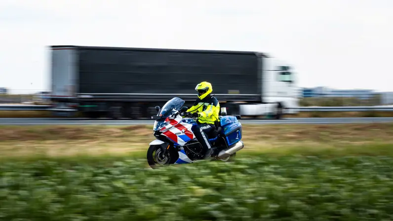 Motorrijder van de Marechaussee rijdt voorbij op zijn motor.