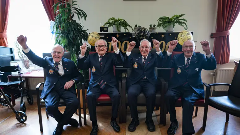 Vier honderdjarige bewoners van Bronbeek poseren tijdens een feestelijke bijeenkomst ter ere van hun honderdste verjaardag.