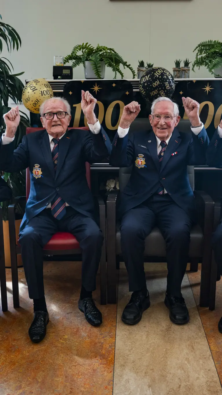 Vier honderdjarige bewoners van Bronbeek poseren tijdens een feestelijke bijeenkomst ter ere van hun honderdste verjaardag.