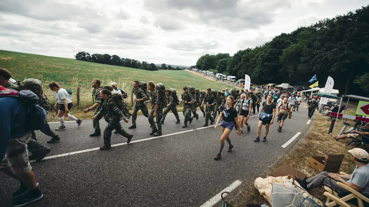 Een groep militairen en burgers loopt over de heuvelachtige weg nabij Groesbeek.