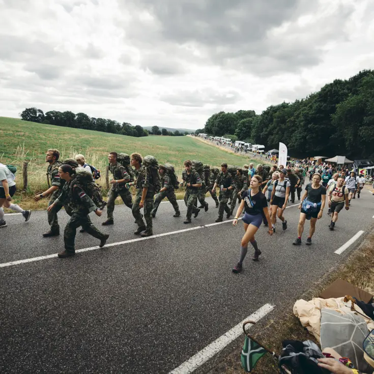 Een groep militairen en burgers loopt over de heuvelachtige weg nabij Groesbeek.