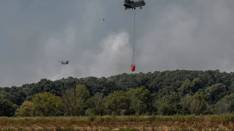 Helikopters vliegen met waterzak boven het water.