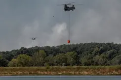 Helikopters vliegen met waterzak boven het water.
