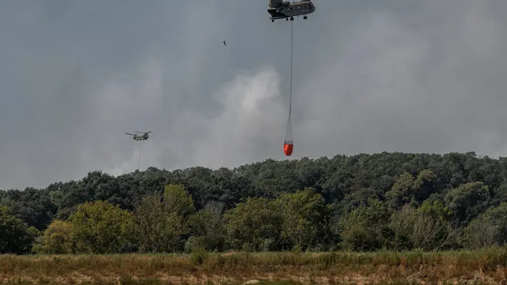 Helikopters vliegen met waterzak boven het water.