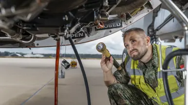 Roy van der Mark met geel hesje aan, schijnt met een zaklantaarn in mortorgondel van een A330 MRTT.