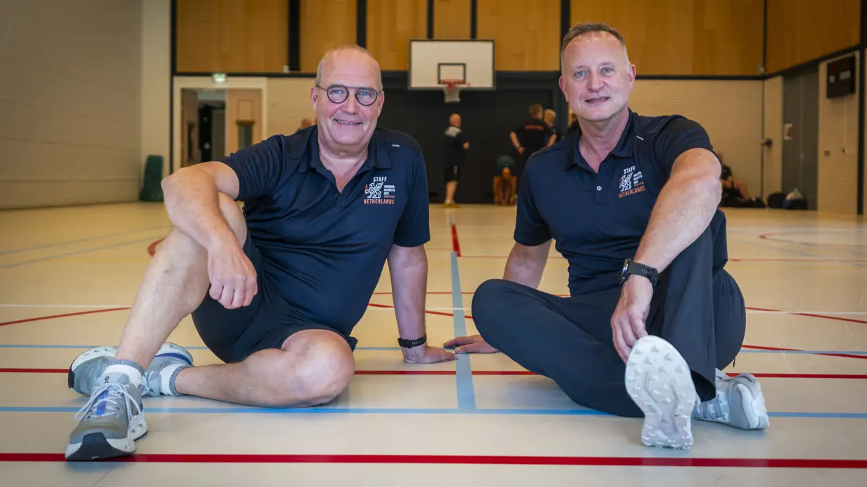 Hoofdtrainer André Wijnberger en teamchef Edwin Wolf zittend op de grond.