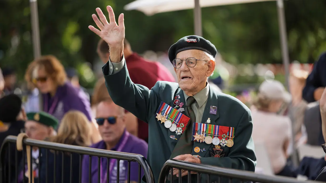 Een oudere veteraan zwaait naar de wandelaars.