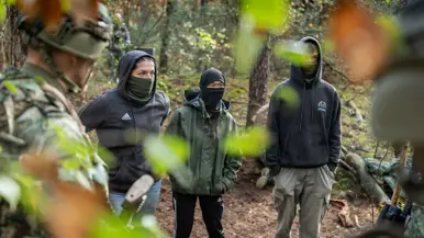 Drie gewapende militairen in gesprek met drie personen in donkere burgerkleding. Een vrouw met een donkere trui en een bedekt gezicht. Militairen in gevecht met de donker geklede partizanen. Twee militairen houden een persoon in burgerkleding vast terwijl diegene met zijn buik op de grond ligt.