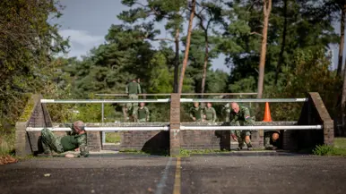 Twee militairen kruipen door een obstakel op de hindernisbaan.