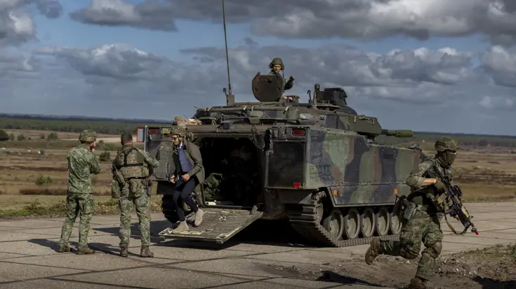 De premier komt een militair voertuig uitgelopen.