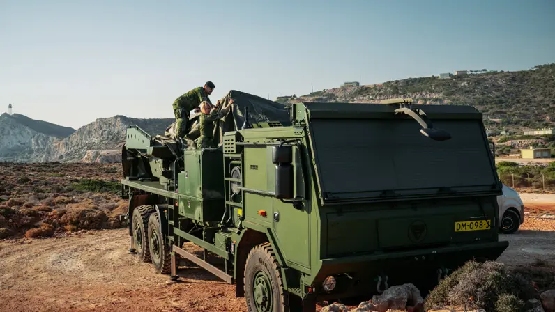 Militairen dekken de lanceerinrichting toe met grote, groene zeildoeken.