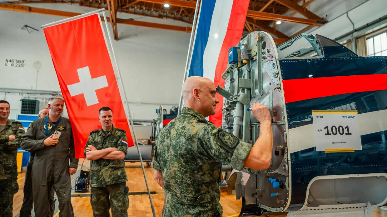 Een militair zet zijn handtekening op de romp van de eerste Nederlandse PC-7 MKX.