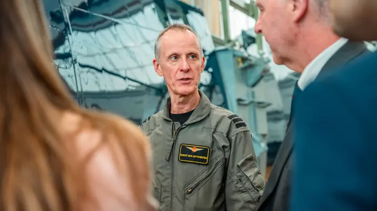 Luchtmachtmilitair staat tussen man in pak en een netjes geklede dame.