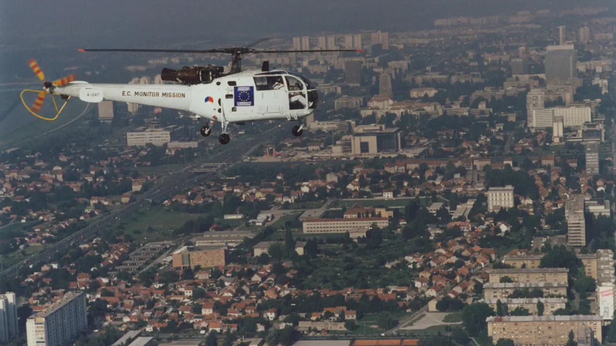 Een witte helikopter vliegt boven een stad.