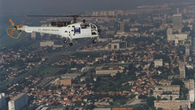 Een witte helikopter vliegt boven een stad.
