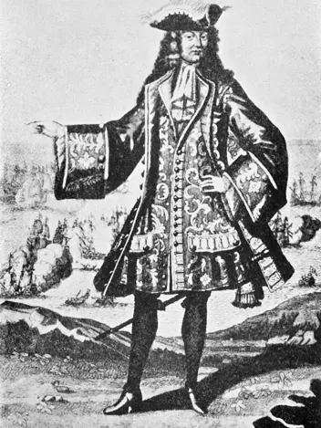 Een man in een weelderig, versierd 17e-eeuws kostuum met een grote pruik, hoed met veren, en een lange jas met ingewikkelde patronen en knopen. Hij staat trots. 