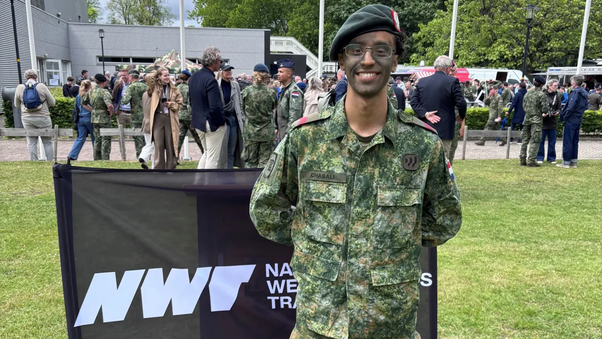 Een militair staat op een grasveld. 