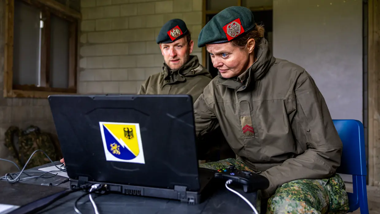 Twee militairen zitten achter een laptop.