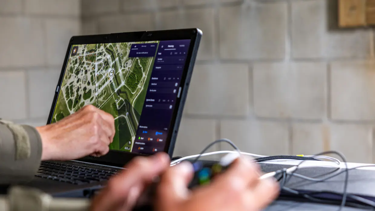 De handen van een militair zijn zichtbaar bij een laptop die een kaart weergeeft.