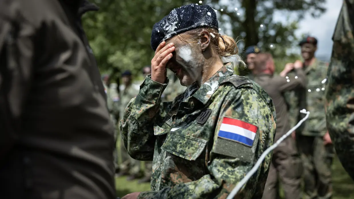 Een vrouwelijke militair met bier op haar schouders, gezicht en baret.