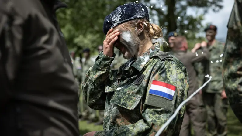 Een vrouwelijke militair met bier op haar schouders, gezicht en baret.
